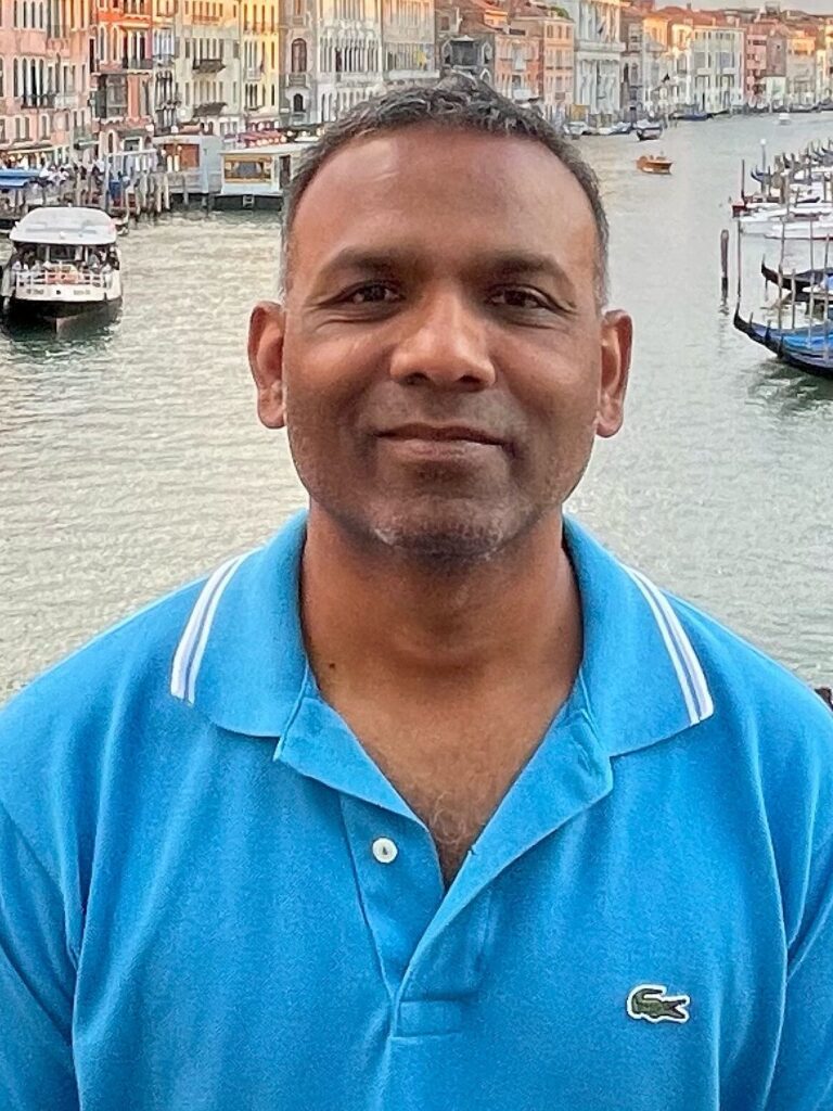 A man in blue shirt standing next to water.